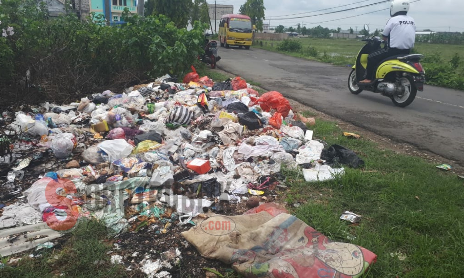 Seorang pengendara sepeda motor melintas di Jalan Arya Wiraraja, Desa Kolor, Sumenep di mana sampah dibiarkan menumpuk. (Foto: Ilyas/SorotPublik)