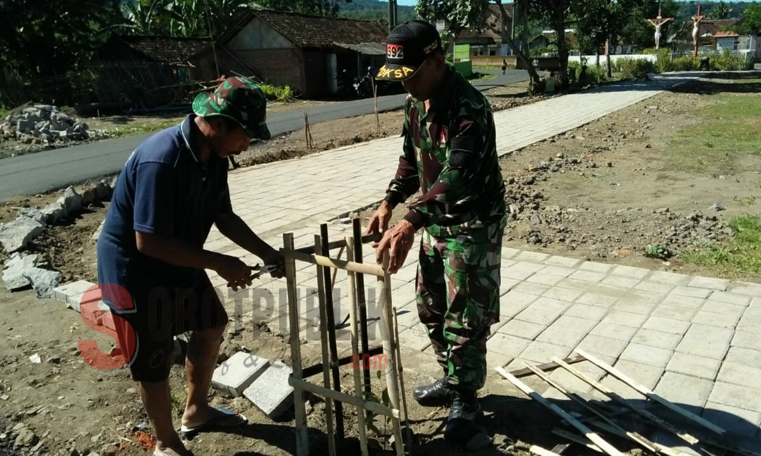 Salah satu warga Desa Gunung Malang didampingi Babinsa setempat sedang membuat pot bunga di lapangan desa yang dibangun Satgas TMMD Jember. (Foto for SorotPublik)