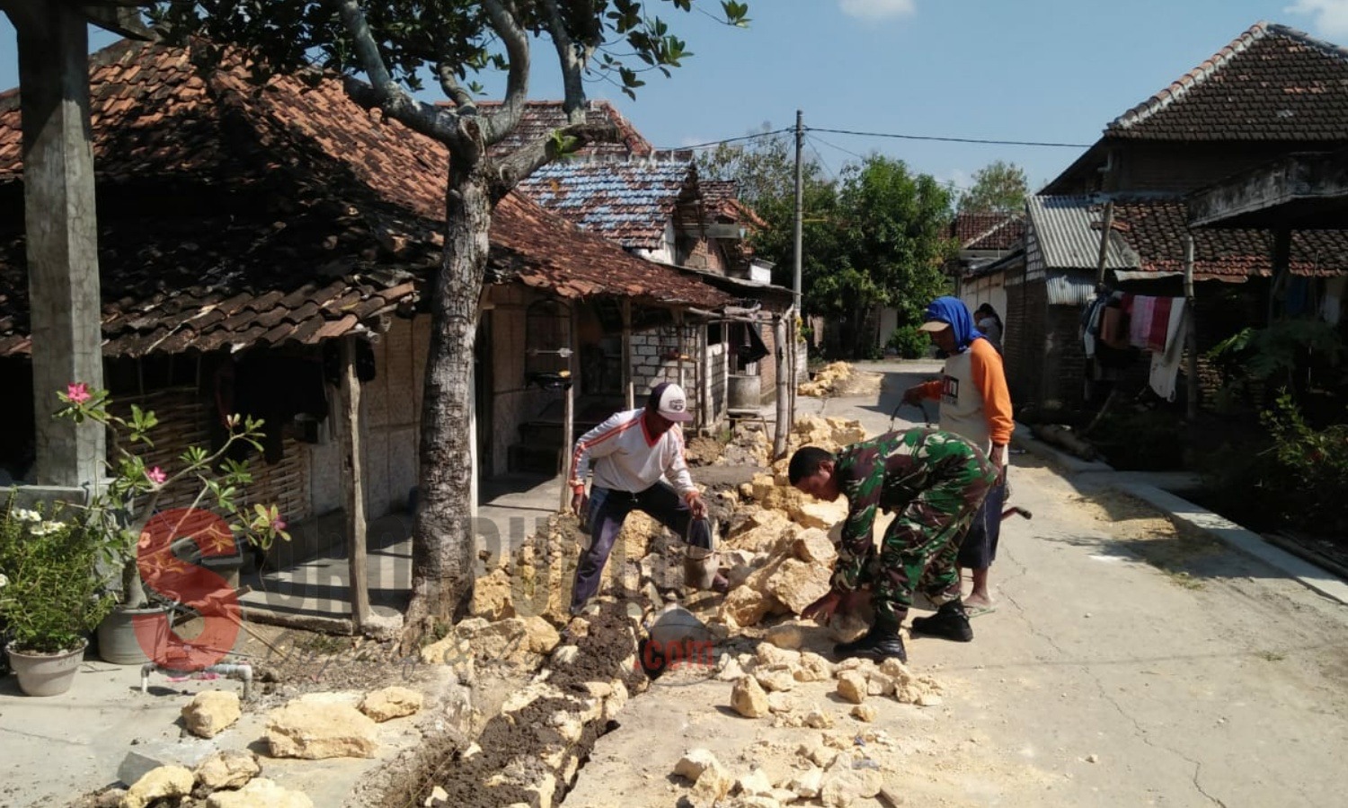 Babinsa Desa Sidodadi, Serka Sugianto saat bergotong royong bersama warga jalan yang rusak di Desa Sidodadi, Kecamatan Mantup, Lamongan. (Foto for SorotPublik)