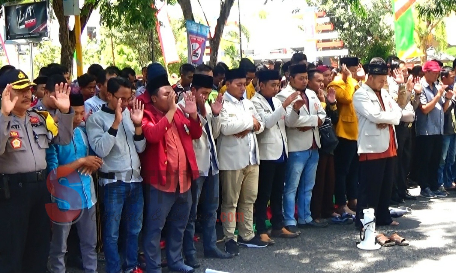 Polisi dan mahasiswa IMM Sumenep saat melakukan shalat gaib di jalan raya depan Mapolres Sumenep. (Foto: Hairul/SorotPublik)