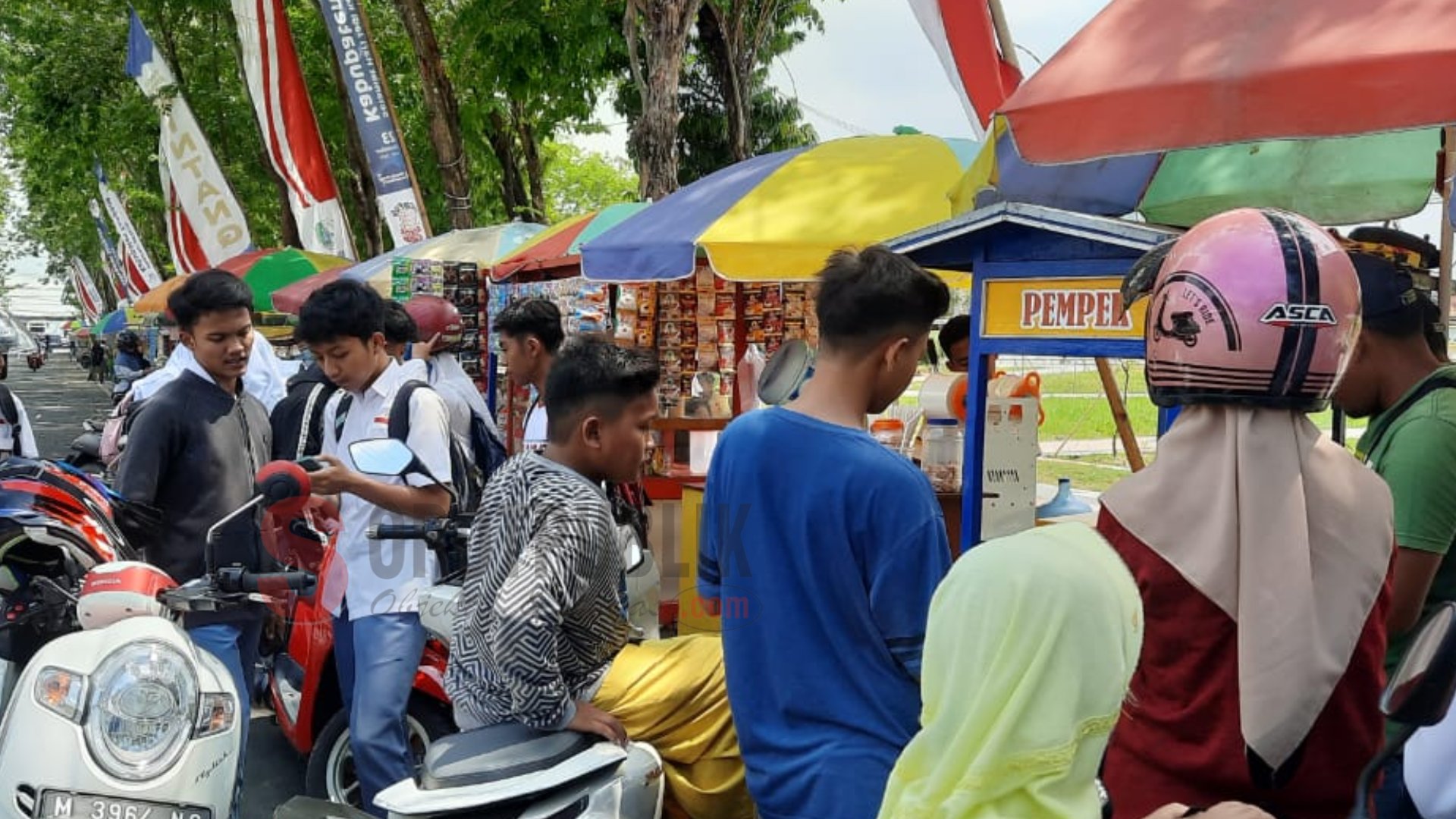 Para pengunjung alun-alun Trunojoyo sedang membeli di pedagang kaki lima.